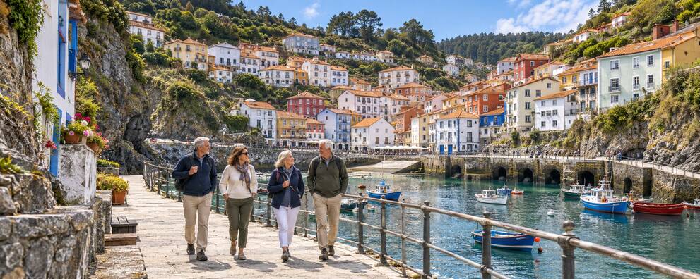Visitantes paseando junto al puerto y las casas de colores de Cudillero
