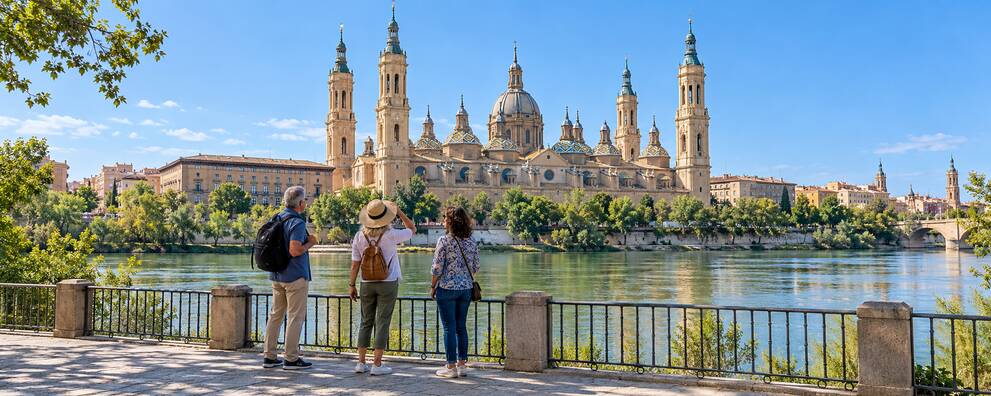 Visitantes contemplando la Basílica del Pilar desde la orilla del Ebro